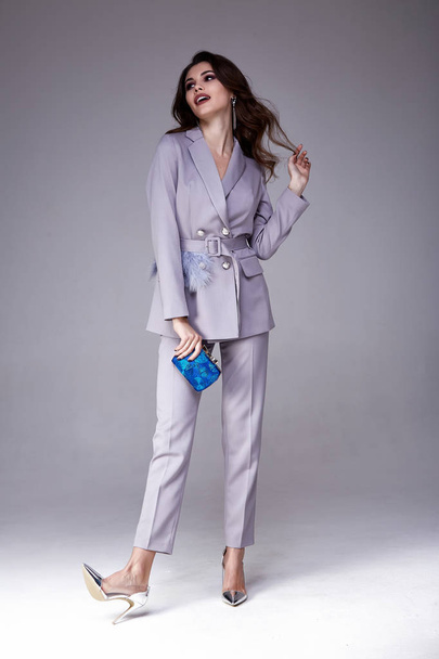 Beautiful sexy pretty girl wear lilac suit jacket and pants skinny body shape lady boss business woman skin tan long brunette hair party style fashion cloches accessory bag jewelry studio background. - 写真・画像
