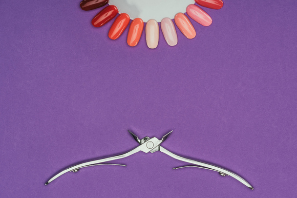 pohled shora kleště na nehty a manikúru palety izolovaných na fialová - Fotografie, Obrázek