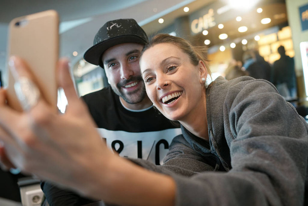 Young couple at the airport connected with smartphone - Foto, afbeelding