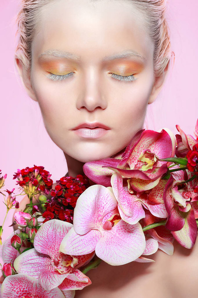 Menina bonita, isolado em um fundo rosa com flores variadas, emoções, cosméticos
 - Foto, Imagem