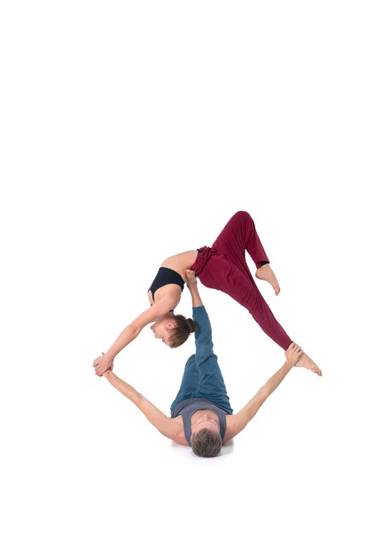 Young athletic couple practicing acroyoga. Balancing in pair - 写真・画像