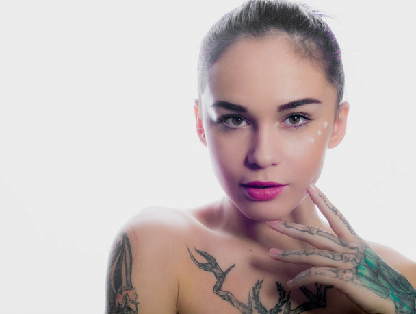 Gyönyörű lány festett haj és tetoválásokat pózol a fehér stúdió - Fotó, kép