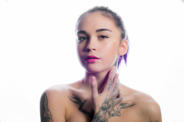 Hermosa chica con el pelo teñido y tatuajes posando en el estudio en blanco
 - Foto, imagen