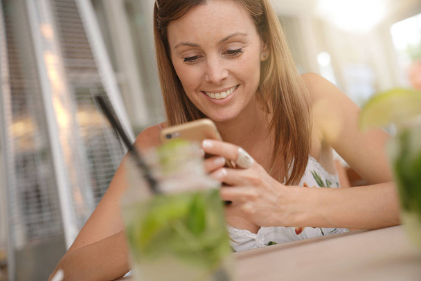 Young woman connected with smartphone in bar - Valokuva, kuva