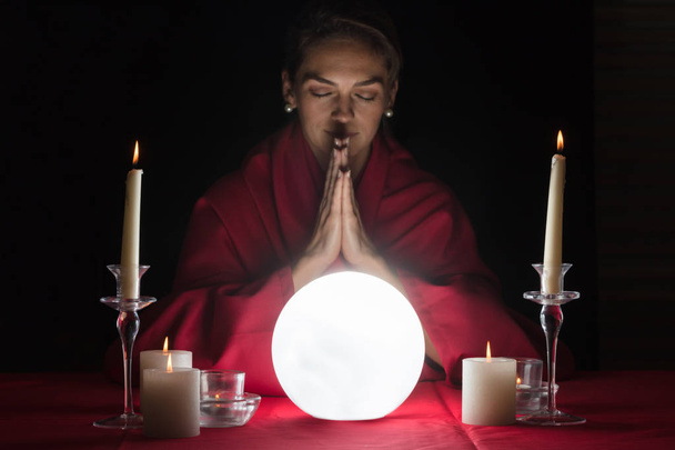 Glowing Crystal Ball In Front Of Woman Fortuneteller With Clasped Hands  - Foto, afbeelding