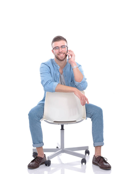 Young man sitting on chair and using mobile phone. Startupper. Young entrepreneur. - Фото, зображення