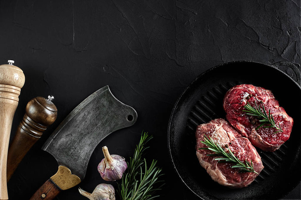 新鮮な生の肉。牛フィレ肉のグリル鍋、切削の斧は、黒の石のテーブルで調理するためのスパイスでの作品。コピー スペース - 写真・画像