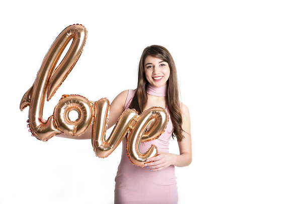 Beautiful millennial female fashion model in stylish clothes posing for 14 february valentines day photo shoot. 90's kid, young woman smiling, laughing, air kiss, holding letter balloons. Copy space. - Foto, immagini