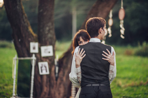 rear view of young caucasian engaged couple hugging under tree in park - Foto, imagen