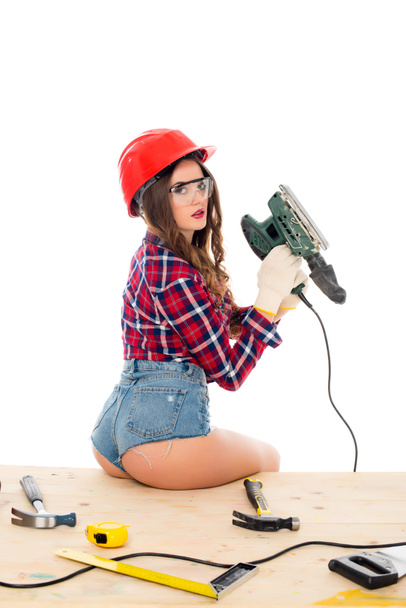 chica sexy posando con herramienta de molienda en la mesa de madera con herramientas, aislado en blanco
 - Foto, Imagen