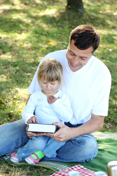 young father with a young daughter read the Bible in nature - Fotografie, Obrázek