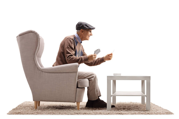 man seated in an armchair playing cards - Φωτογραφία, εικόνα