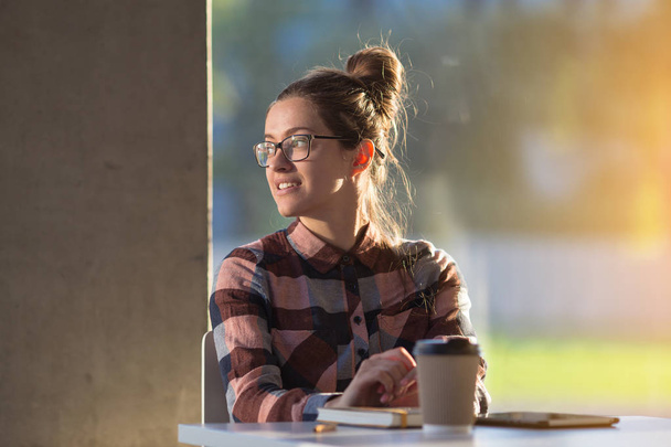 Молодая студентка пьет кофе в стеклянном интерьере
 - Фото, изображение
