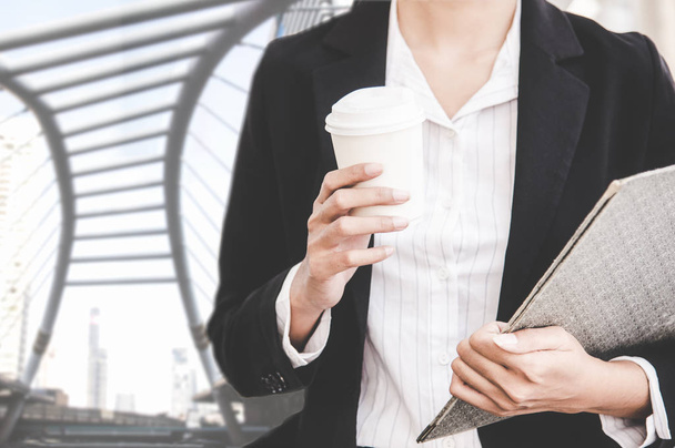 Close up of businesswoman holding a coffee cup and document report walking in the cityscape haste time.   Business and Lifestyle Concept - Foto, Imagem