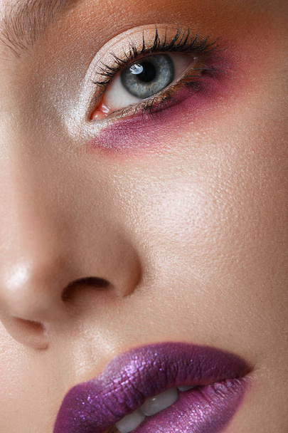 Beautiful blonde girl with purple lips and art creative make-up. Beauty face. - Фото, изображение