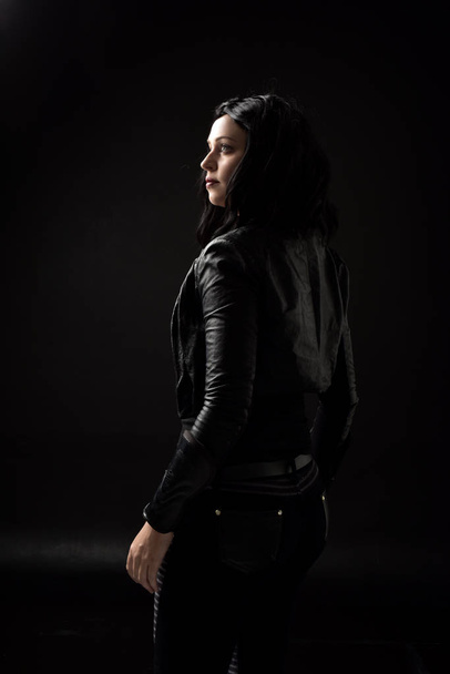 portrait of black haired girl wearing leather clothes, moody lighting on black background. - Fotografie, Obrázek