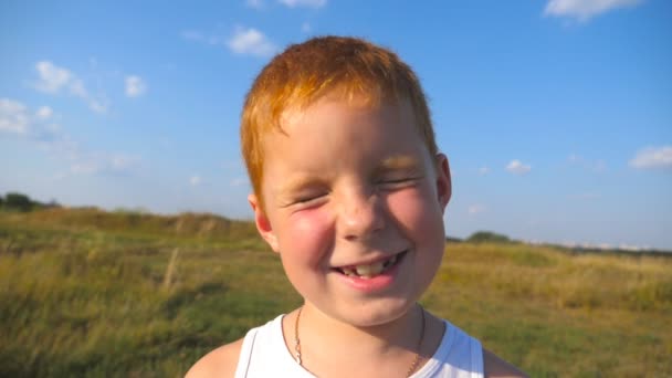 Érzelmek az arcán boldog kifejezés gyermek közelről. Boldog vörös hajú fiú szeplő portréja szabadtéri nevet. Imádnivaló szép baba látszó-ba kamera örömteli mosollyal. Lassú mozgás - Felvétel, videó