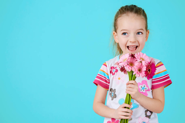 Adorable little girl with cheeky smile and face expression holding bouquet of pink gerbera daisies. Happy Mother's Day, Women's day, Father's day or Birthday background. - Foto, imagen