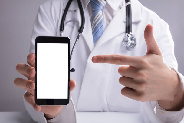Close-up Of A Doctor's Hand Showing Blank White Mobile Screen - Foto, afbeelding