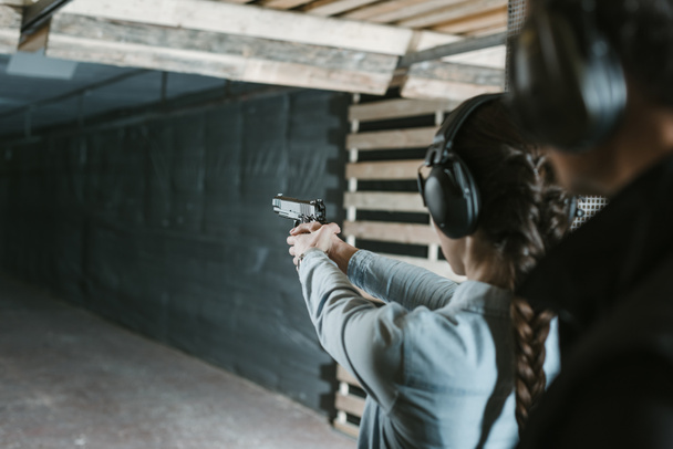 rear view of girl shooting with gun in shooting gallery - Foto, Imagen