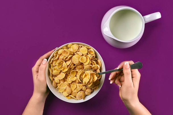 Comida, alimentação saudável, pessoas e conceito de dieta - close-up de mulher comendo muesli com leite para o café da manhã sobre fundo roxo
 - Foto, Imagem
