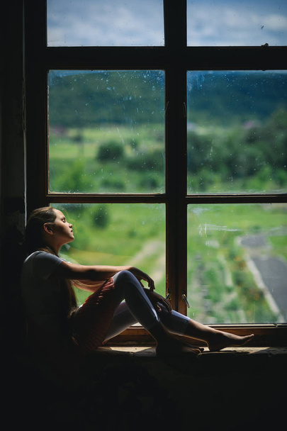 Young girl sleep on window sill with summer landscape view - Φωτογραφία, εικόνα