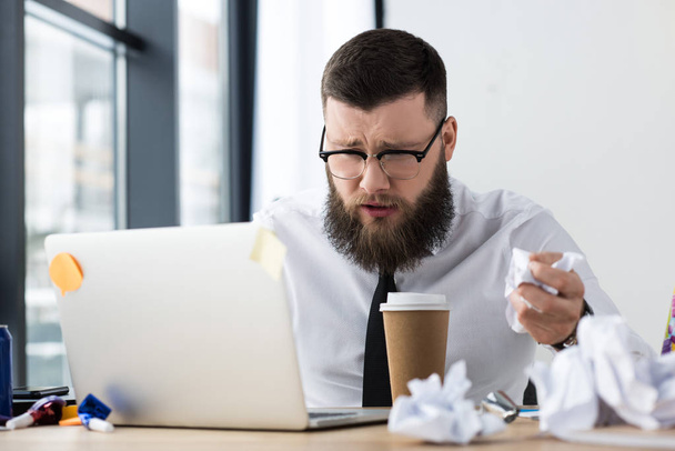 retrato de hombre de negocios con exceso de trabajo en el lugar de trabajo con ordenador portátil y café para ir en la oficina
 - Foto, Imagen
