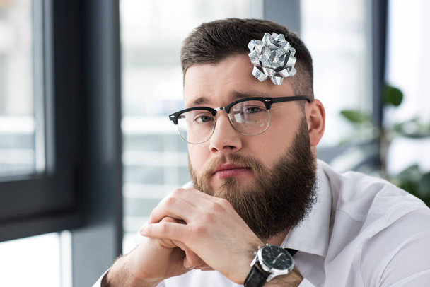 portrait of bearded businessman with bow on head looking at camera in office - Photo, Image