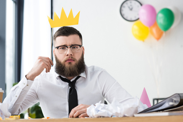 portrait of businessman with paper crown at workplace in office - 写真・画像