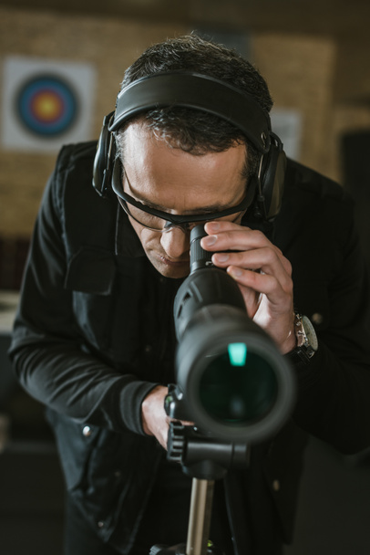 hombre mirando a través de binoculares en el campo de tiro
 - Foto, Imagen