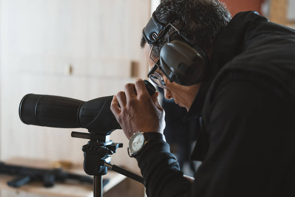 man looking through binoculars in shooting range - Photo, Image