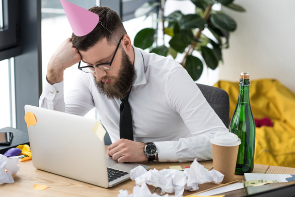 businessman with paper cone on head sleeping at workplace - Foto, Bild