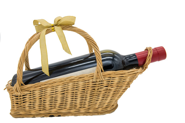 籐にワインのボトルは、ゴールド リボンまたはコピーのテキストのための領域の白い背景に分離されたリボン付きバスケットを織り。バレンタイン甘いカップルの休日のお祝いのための特別な贈り物. - 写真・画像