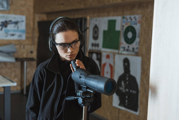 attractive woman with binoculars in shooting range - Photo, Image