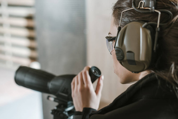 vista lateral de la mujer con prismáticos en el campo de tiro
 - Foto, Imagen