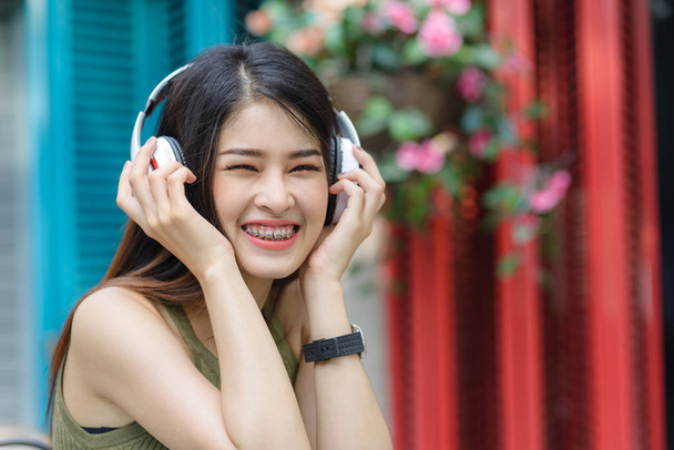 Mujer asiática feliz escuchando música con outdo de fondo de color
 - Foto, imagen