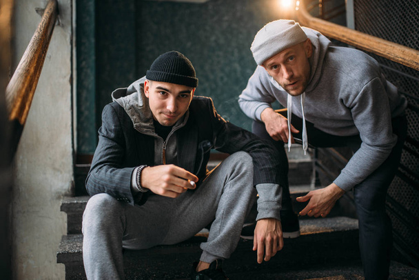 Два грабителя-мужчины на лестнице. Уличные бандиты в ожидании жертвы, концепция преступления
 - Фото, изображение