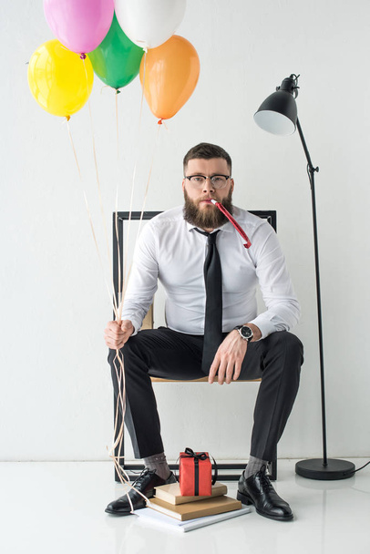 businessman in formal wear with balloons sitting on chair - Foto, imagen