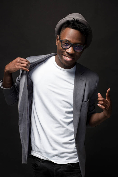 Attractive young black male studio with hat cheesy smile on dark background - Foto, imagen