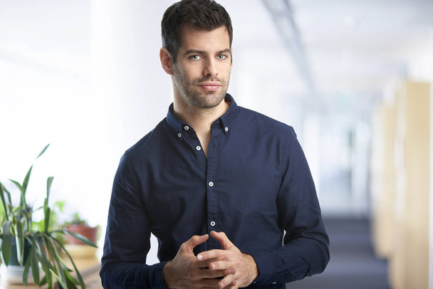 Confident young financial assistant businessman wearing shirt and looking at camera while standing at the office.  - Foto, Bild