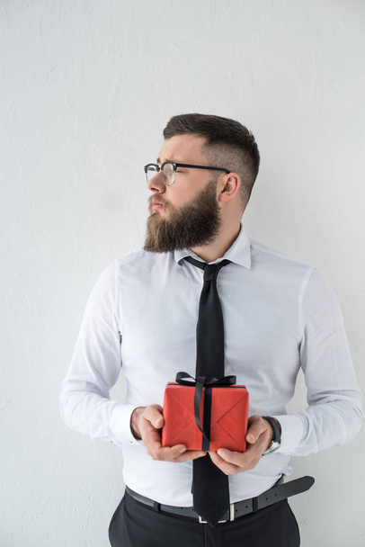 portrait of pensive businessman with wrapped present in hands isolated on white - Photo, Image