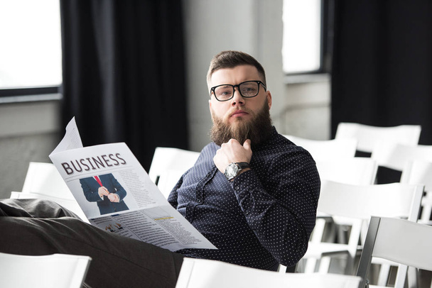 portrait of pensive bearded businessman with newspaper sitting in meeting room - Foto, Imagem