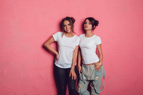 Attractive women in a white t-shirts stands on a pink background. Mock-up. - Φωτογραφία, εικόνα