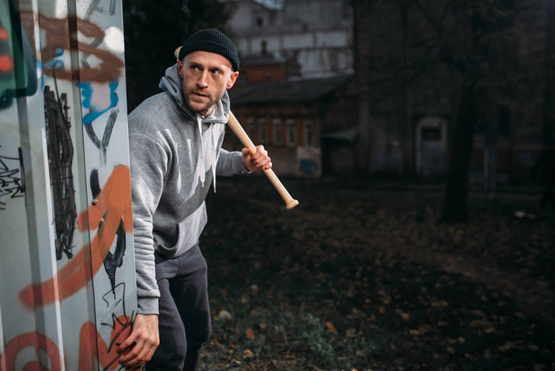 ladrão do sexo masculino com bastão de beisebol esperando vítima na rua noturna, conceito de crime, assalto ataque perigo
 - Foto, Imagem