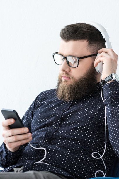 портрет человека со смартфоном, слушающего музыку в наушниках
 - Фото, изображение