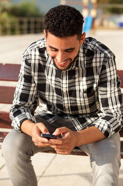 Boldog Észak-afrikai fiatalember nézett cellphone portréja - Fotó, kép