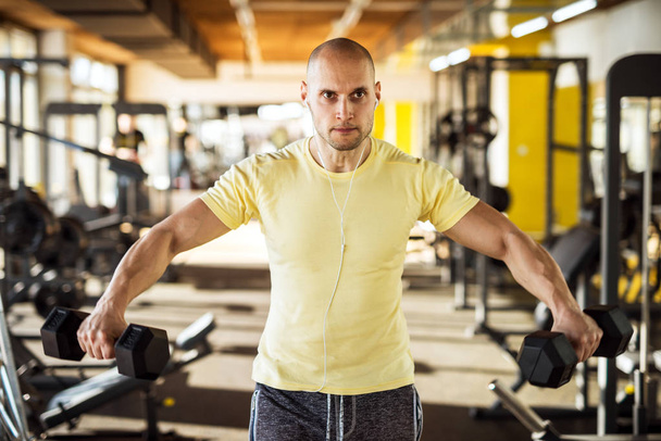 fuerte musculoso hombre ejercitando con mancuernas en gimnasio
  - Foto, Imagen