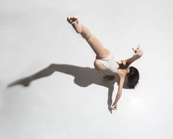 Young beautiful dancer in beige dress dancing on gray background - Foto, immagini
