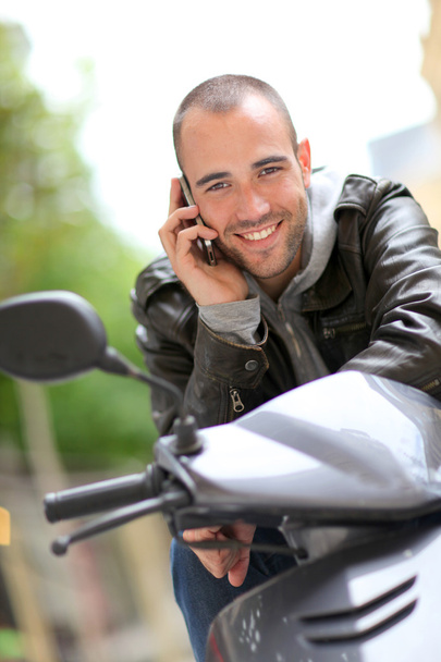 Young man sitting in motorcycle with telephone - Fotoğraf, Görsel