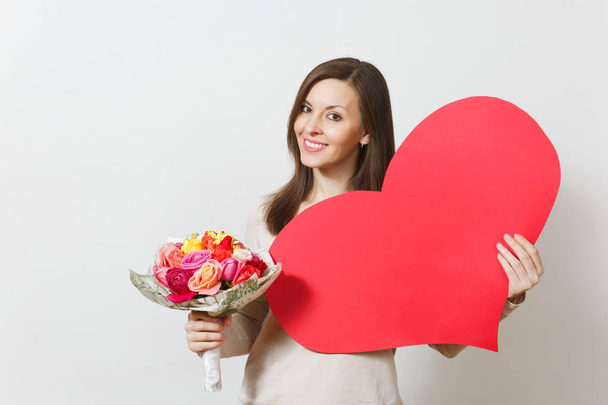 junge hübsche Frau mit einem großen roten Herz, einem Strauß schöner Rosen auf weißem Hintergrund. Kopierfläche für Werbung. Platz für Text. St. Valentinstag oder Internationaler Frauentag - Foto, Bild